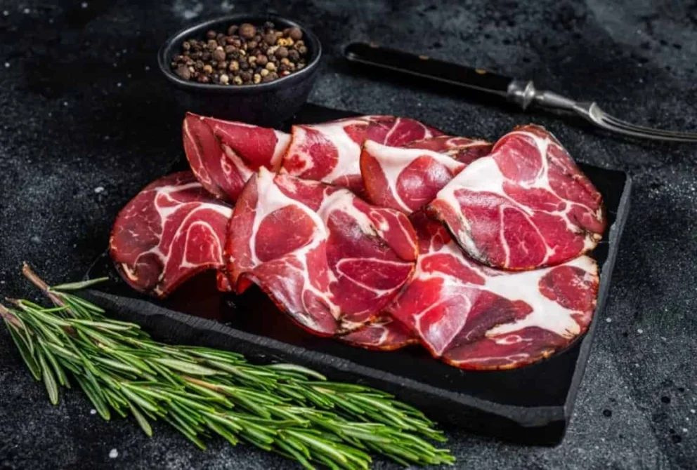 Fette di coppa affettata su un tagliere, salume italiano caratterizzato da diverse proprietà nutrizionali.