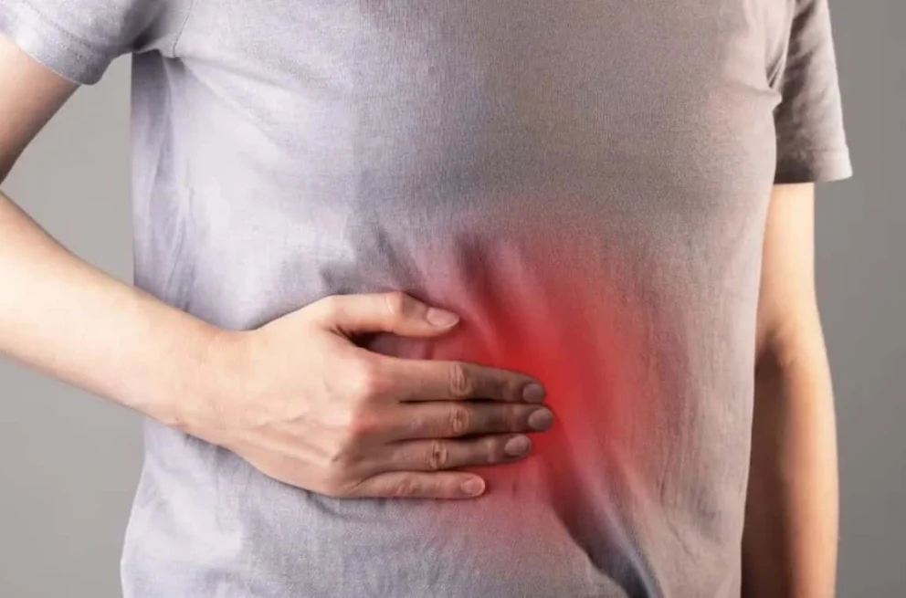 ersona che si tocca il fianco destro, con un’area evidenziata in rosso a indicare dolore localizzato tipico del fegato ingrossato